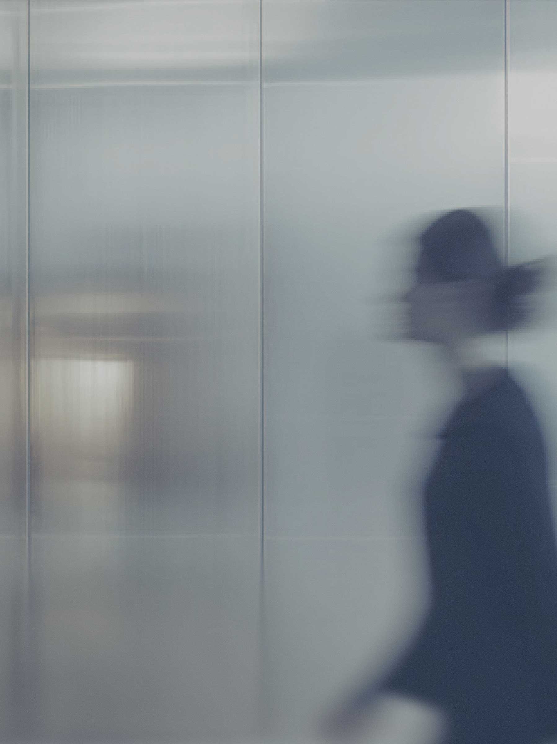 Blurred figure walking through a modern, glass-walled office space, conveying security and professionalism